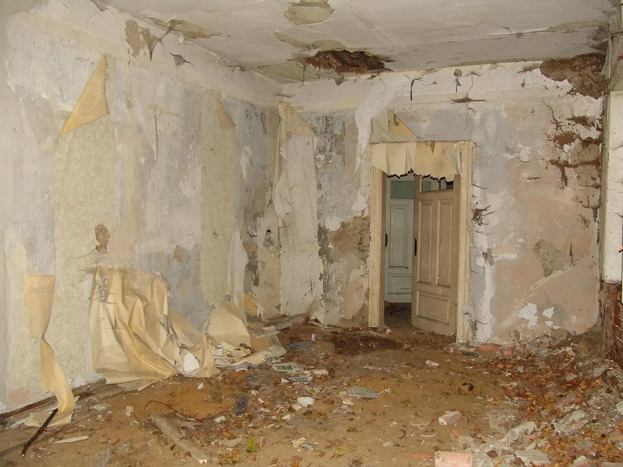 Rum med gammelt afskallet tapet og beskadigede vægge